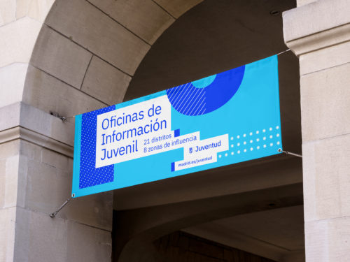 Diseño de comunicación corporativa del Área de Juventud del Ayuntamiento de Madrid, aplicado a una lona en la fachada de un edificio